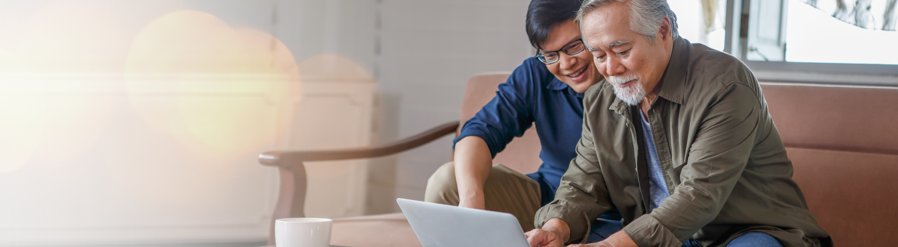 Older adults looking at content on laptop sitting on couch